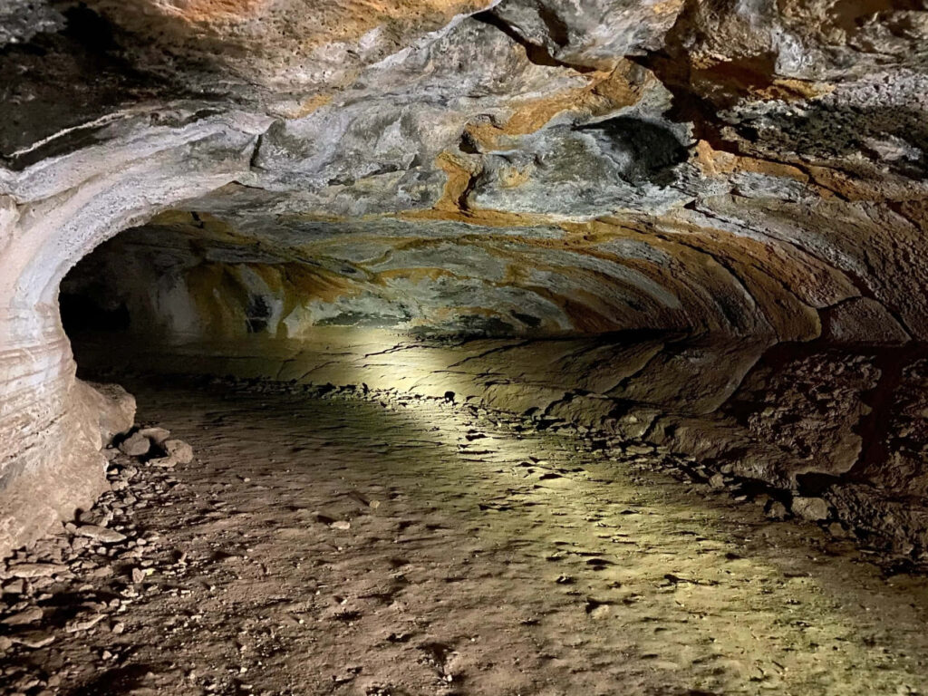 Sunlit Cave Entrance: Explore Intricate Rock Formations & Rugged Terrain Wallpaper