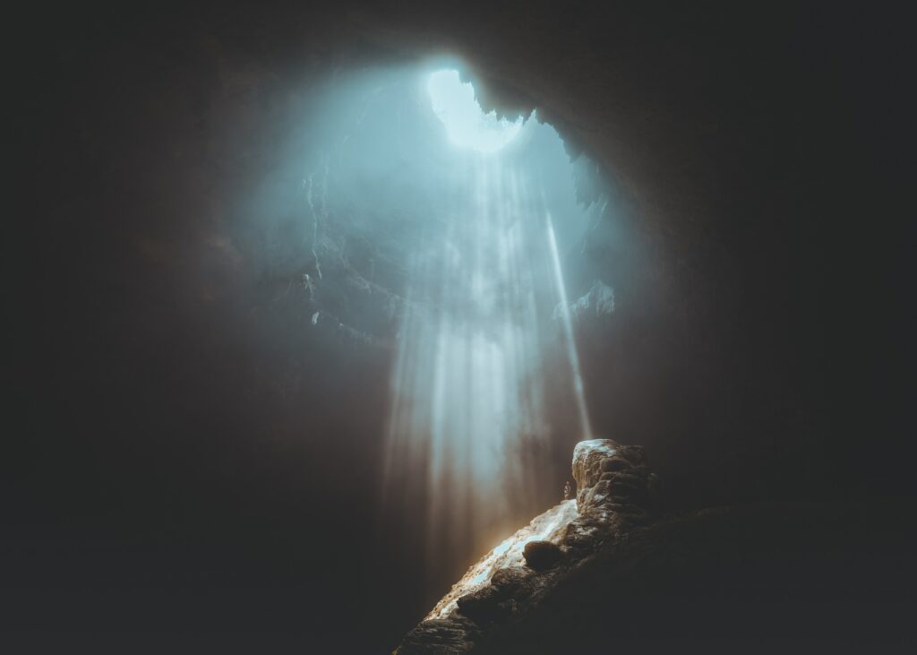 Sunlight streaming into cave interior illuminates jagged rocks creating dramatic textured contrast Wallpaper