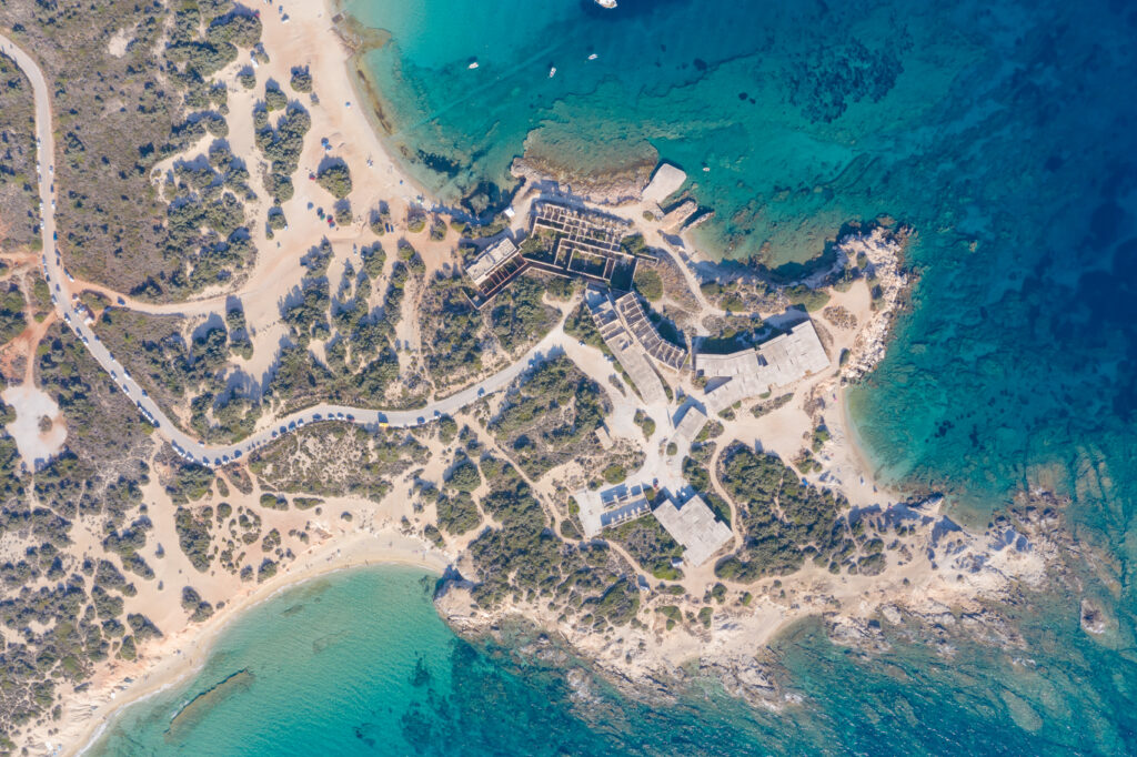 Aerial view of sunlit island with sandy beaches turquoise sea rustic buildings and lush vegetation Wallpaper