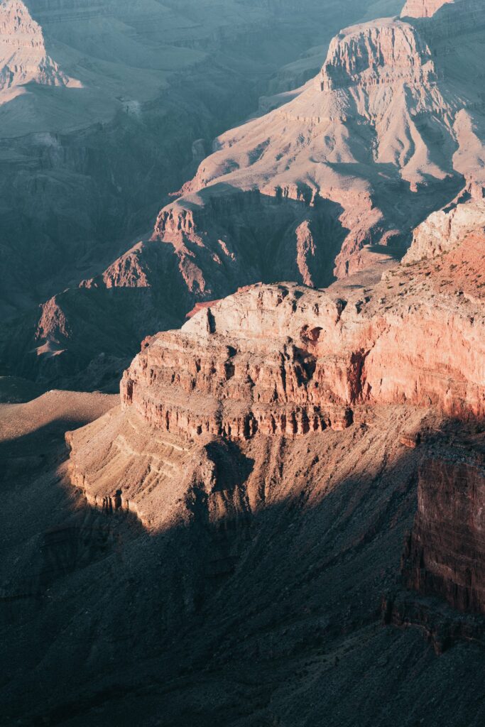 Stunning mountain landscape with rugged rocks deep gorges and warm sunlight highlighting textures Wallpaper
