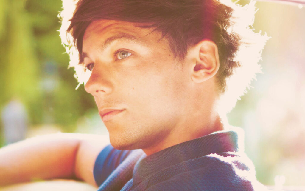 Radiant Charm: Louis Tomlinson's Sunlit Side Profile in a Blue Polo Shirt Wallpaper