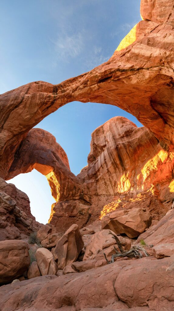 Striking sandstone arches over rugged canyon with red and orange rocks under clear blue sky wallpaper