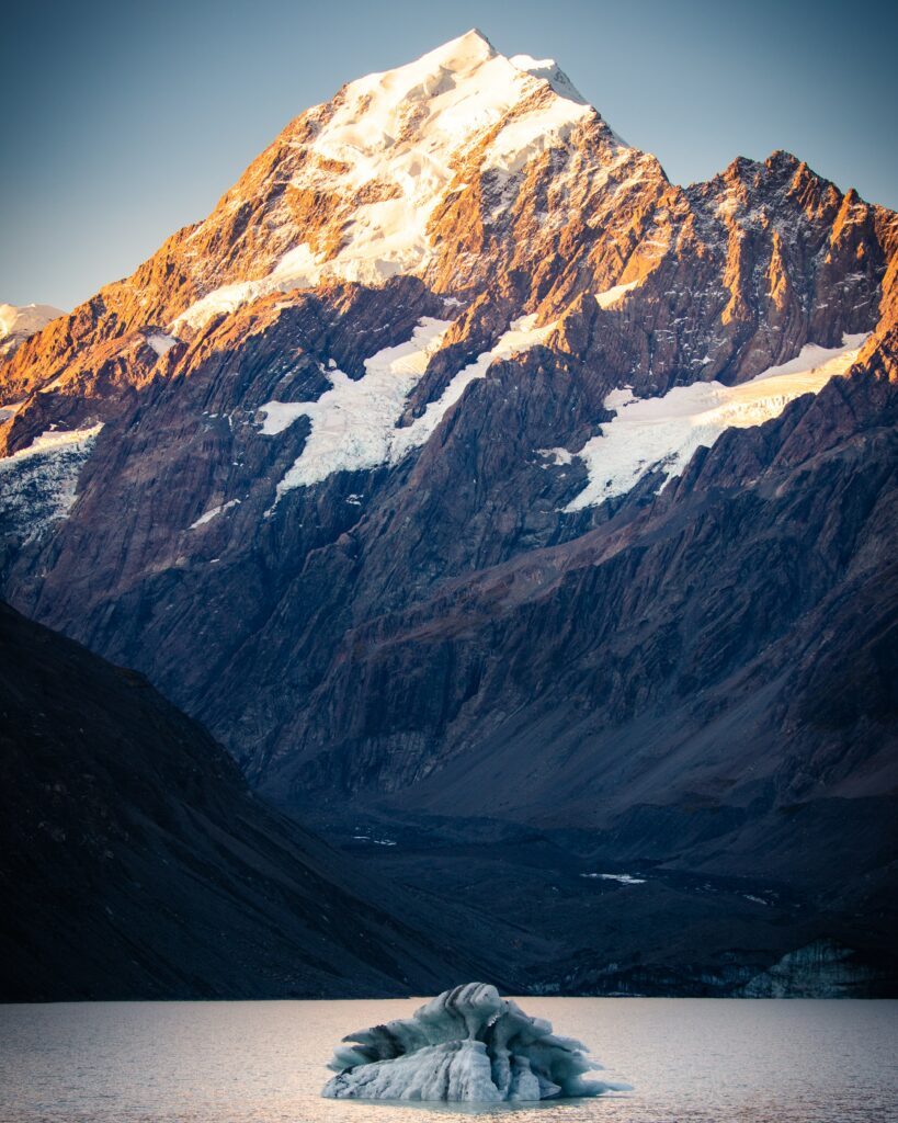 Sunlit rugged snow-capped mountain peak with dramatic slopes and cliffs at golden dawn wallpaper