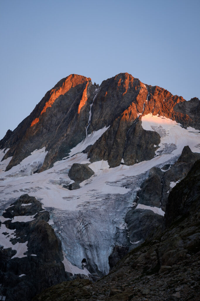 Dramatic mountain peak with rugged rocks snow slopes warmly lit winter landscape wallpaper background