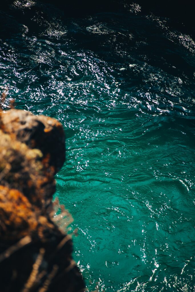 Sunlit ripples on clear turquoise water with warm rugged rock adding natural texture background Wallpaper