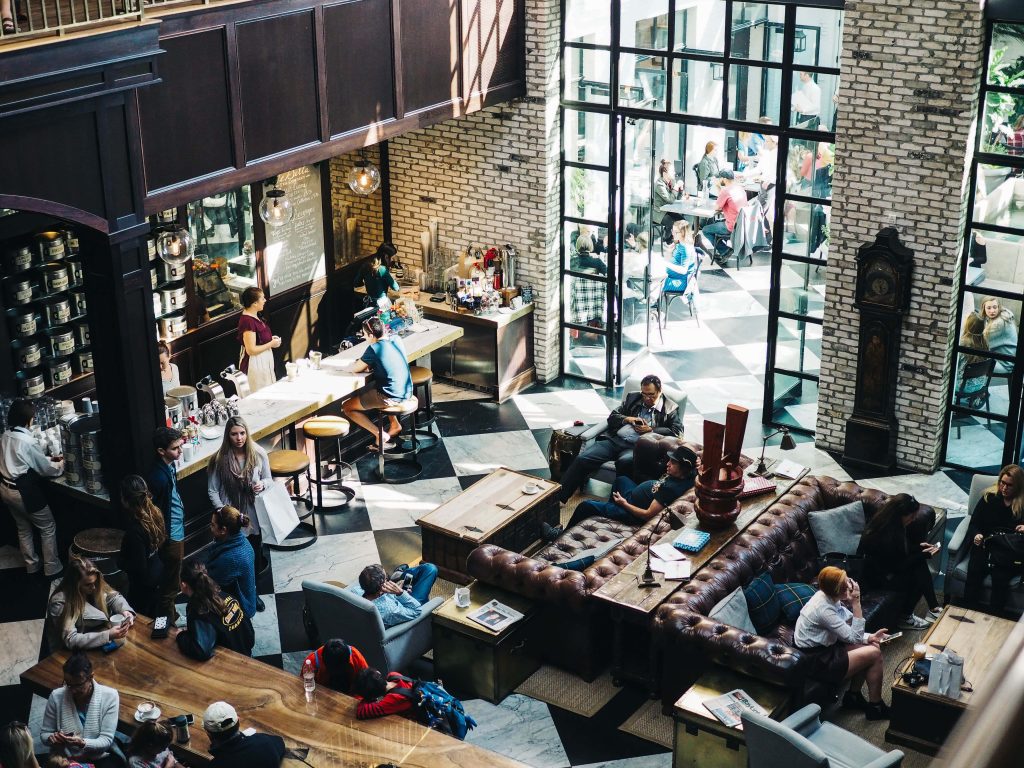 Sunlit two-floor coffee shop with industrial chic decor and cozy leather lounge background Wallpaper