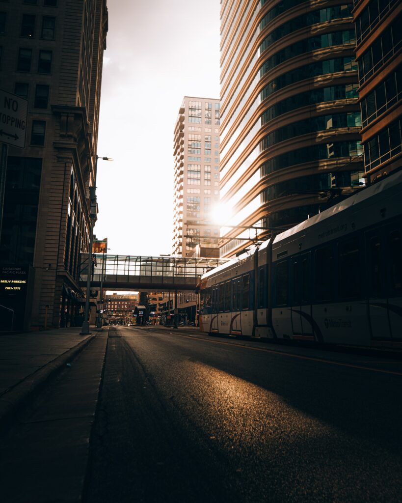 Urban Wallpaper: Sunlit Road & Train Among Tall City Buildings