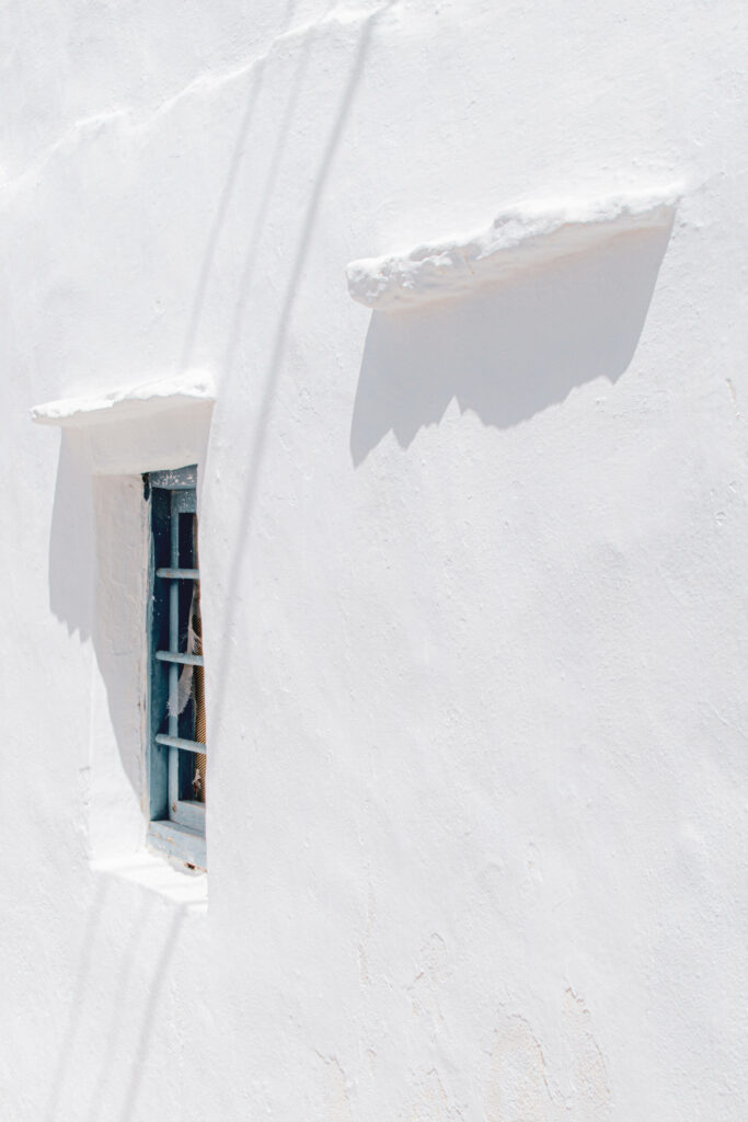 Serene Tranquility: A Vintage Blue Window Basks in the Sun amidst Santorini-inspired White Aesthetics Wallpaper