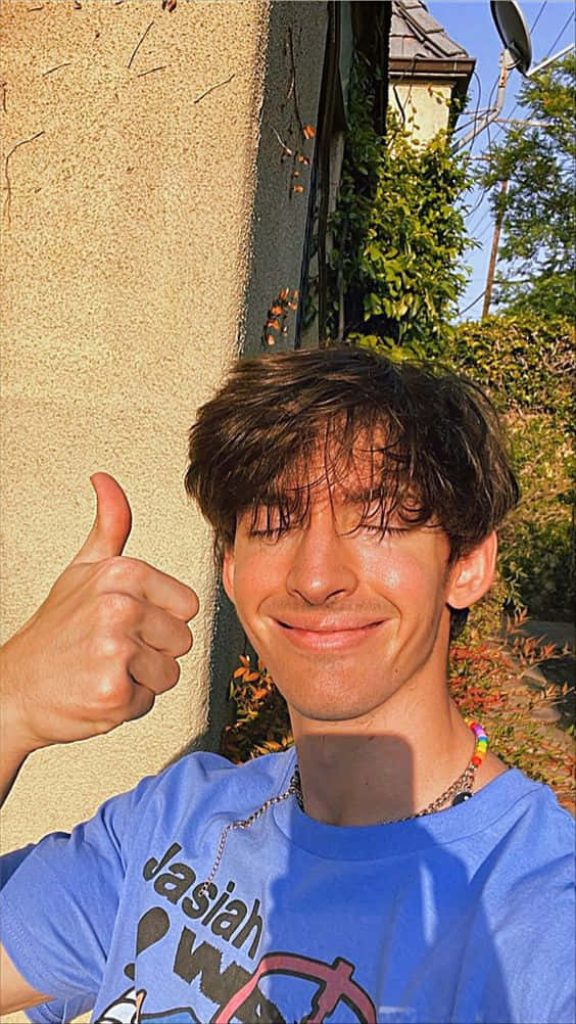 Flamingo YouTuber Albert Aretz outdoor selfie thumbs up light blue Jasiah shirt rainbow beads Wallpaper