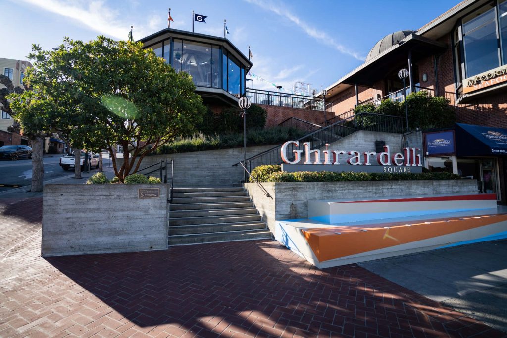 Sunny Ghirardelli Square San Francisco with iconic sign vibrant seating and clear blue sky Wallpaper