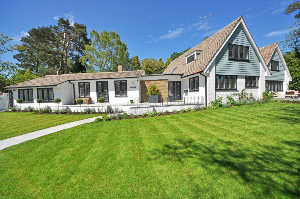 Sunlit Little Rambles home with white brick blue cladding lush garden and vibrant lawn wallpaper