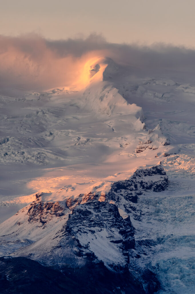 Sunrise over snow-covered mountain slope showcasing rugged textures and warm golden hues wallpaper