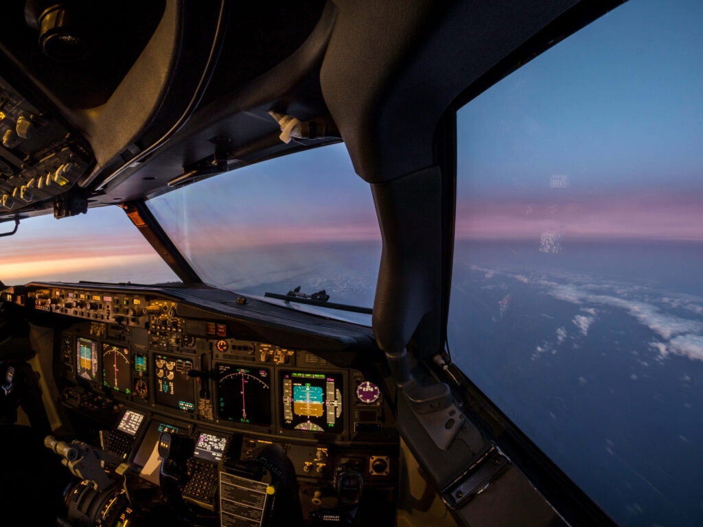 Sunset sky from airplane cockpit with glowing flight instruments and vibrant orange pink blue hues Wallpaper