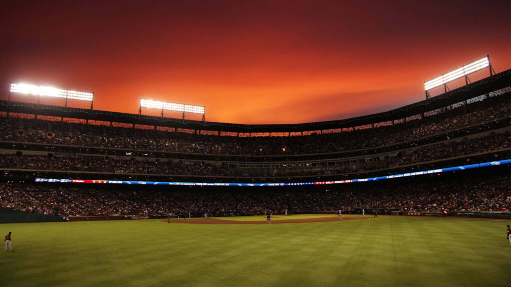 Sunset over baseball stadium with vibrant crowd glowing lights and players ready for game night Wallpaper