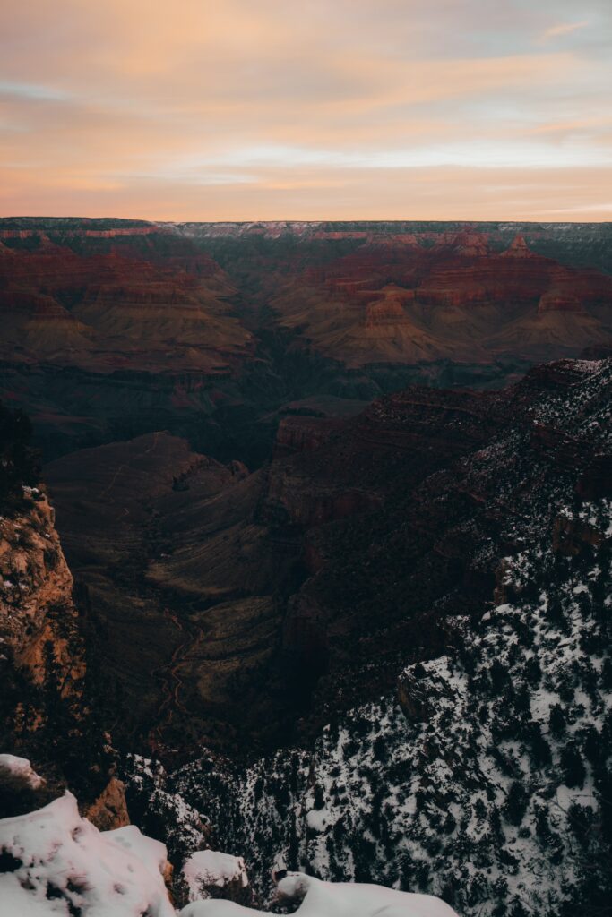 Aerial view of snow-dusted canyon and valley with rugged mountains in warm sunset light wallpaper