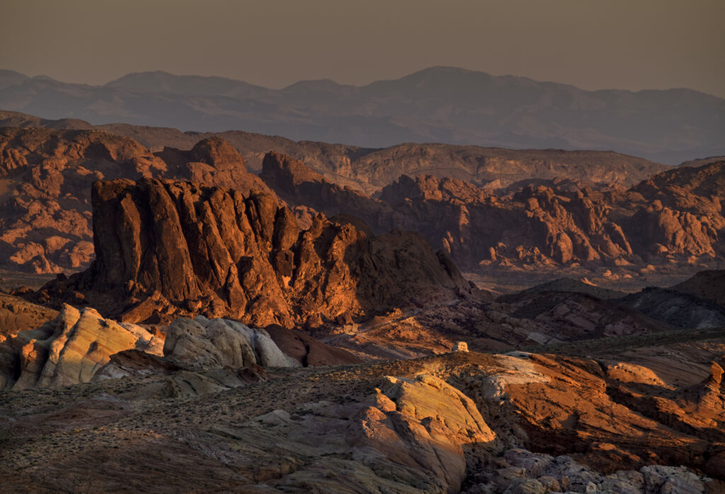 Sunset canyon landscape with rugged rocks and towering mountains in warm orange hues wallpaper