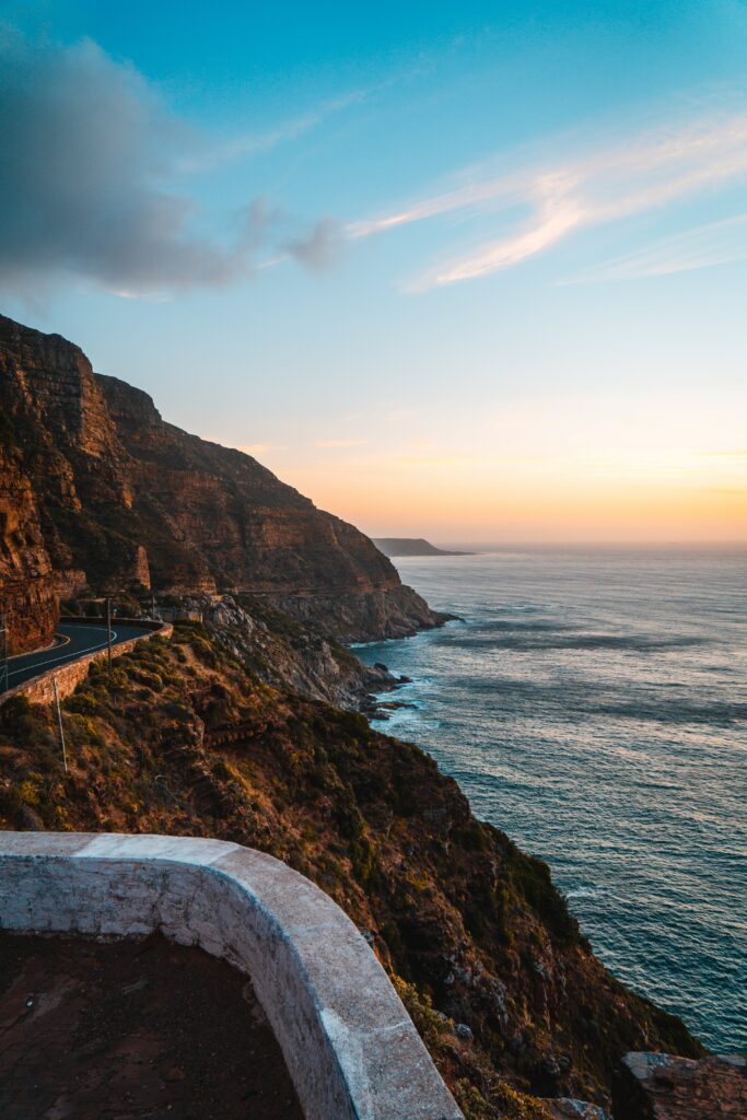 Sunset coastal cliffs with winding road over calm sea golden light serene adventure wallpaper