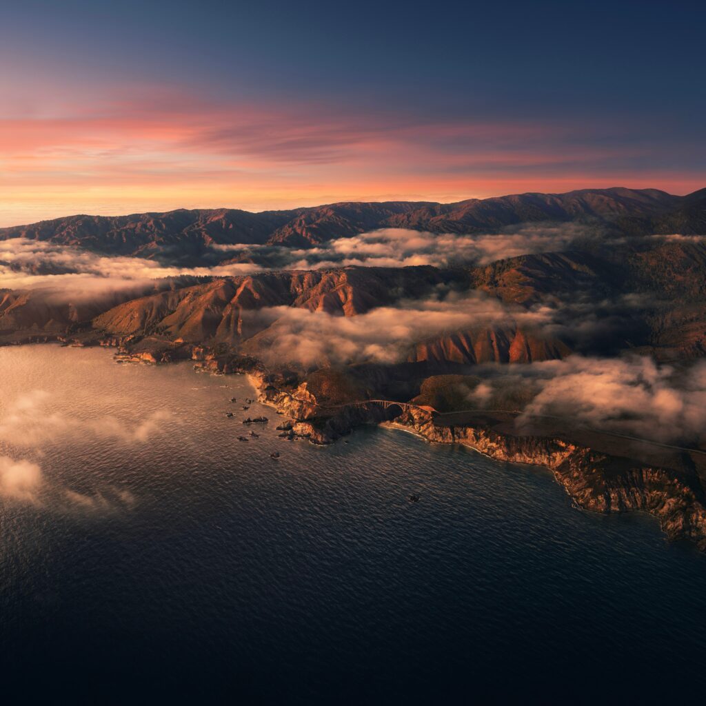 Dramatic coastal cliffs at sunset with soft clouds and warm orange blue hues wallpaper background