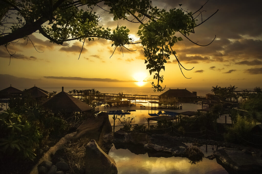 Coastal sunset wallpaper with charming houses lush trees and reflections in calm tropical water