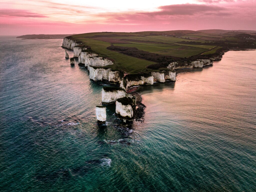 Sunset coastal wallpaper with rugged white cliffs rocky formations and serene island view