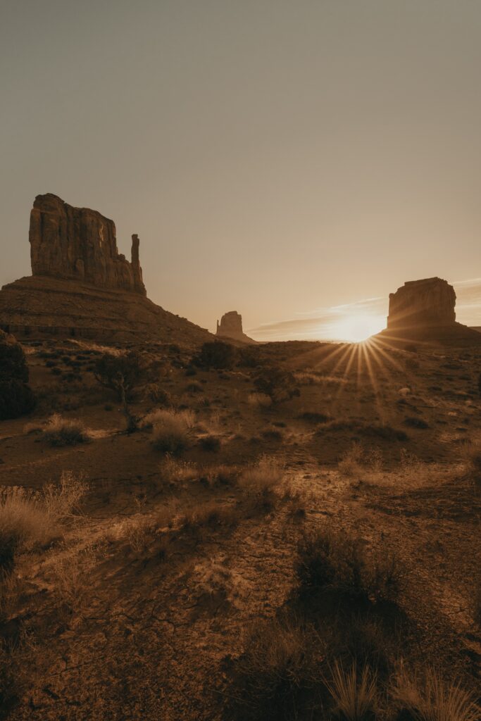 Sunset over desert canyon with golden light illuminating rugged rocks and dry grassy plains Wallpaper
