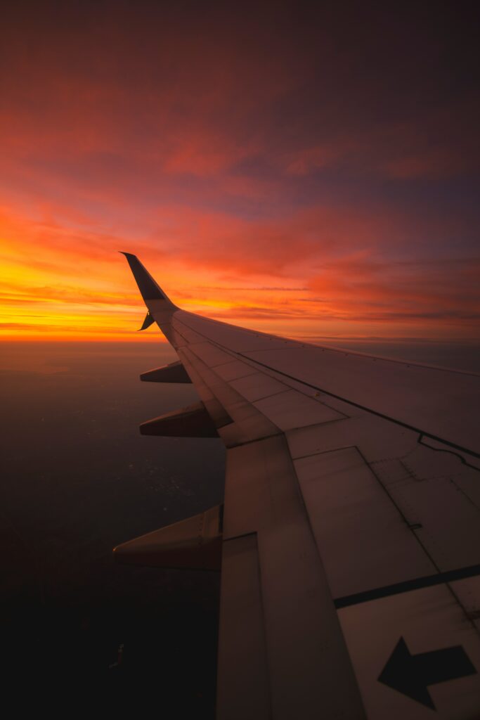 Sunset view from airplane wing over vibrant orange and red clouds serene sky flight wallpaper