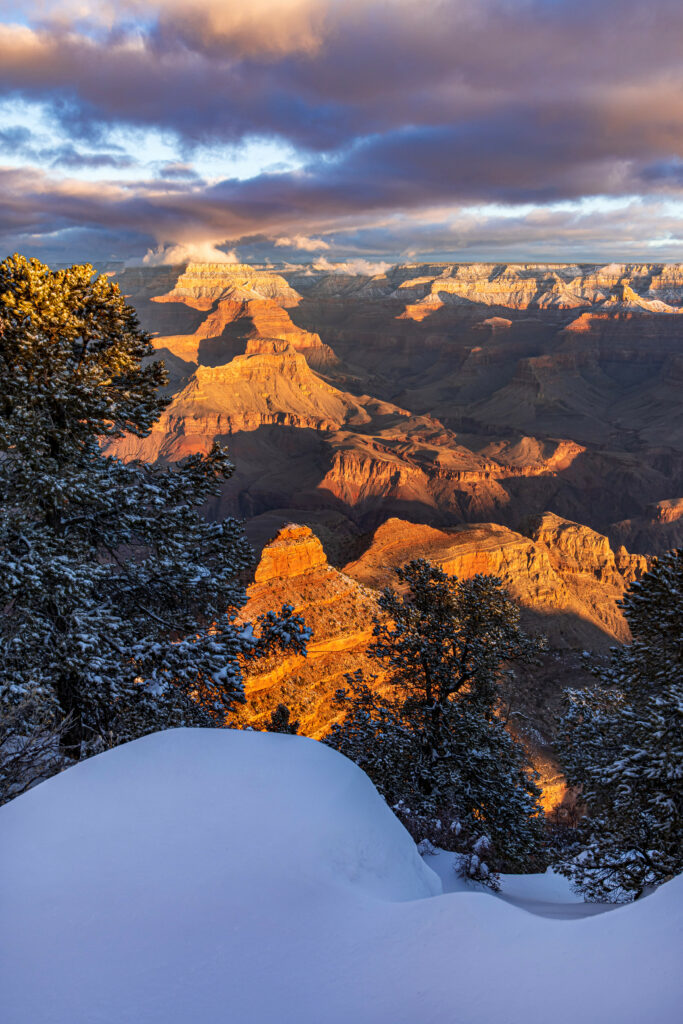 Aerial view of snow-covered mountain canyon at sunset with golden light and dramatic cliffs Wallpaper