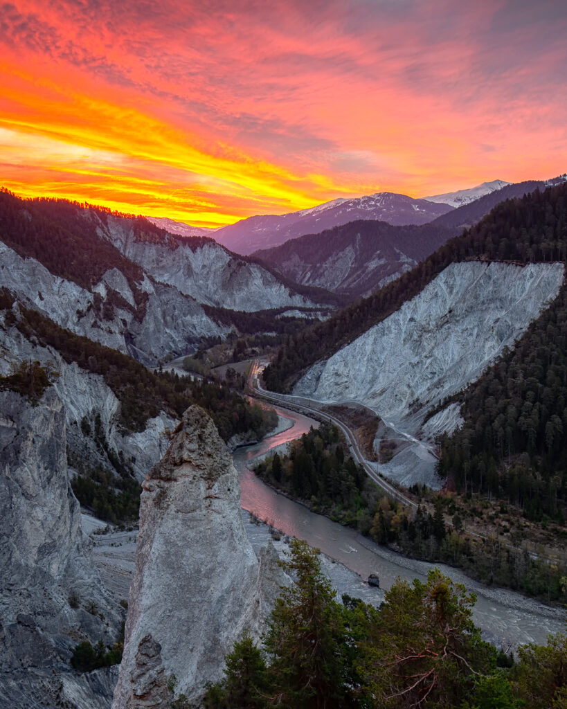 Sunset landscape with rugged rocks winding river and dense forested mountains in dramatic valley Wallpaper