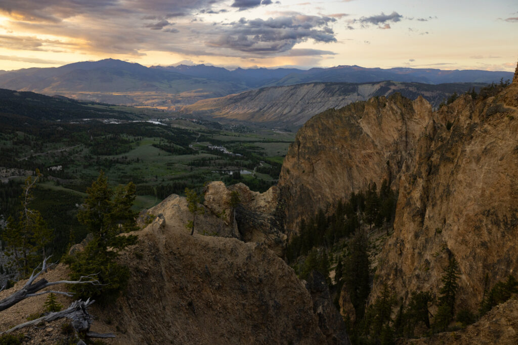 Sunset mountain landscape with rugged rocks lush valley winding river earthy tones wallpaper