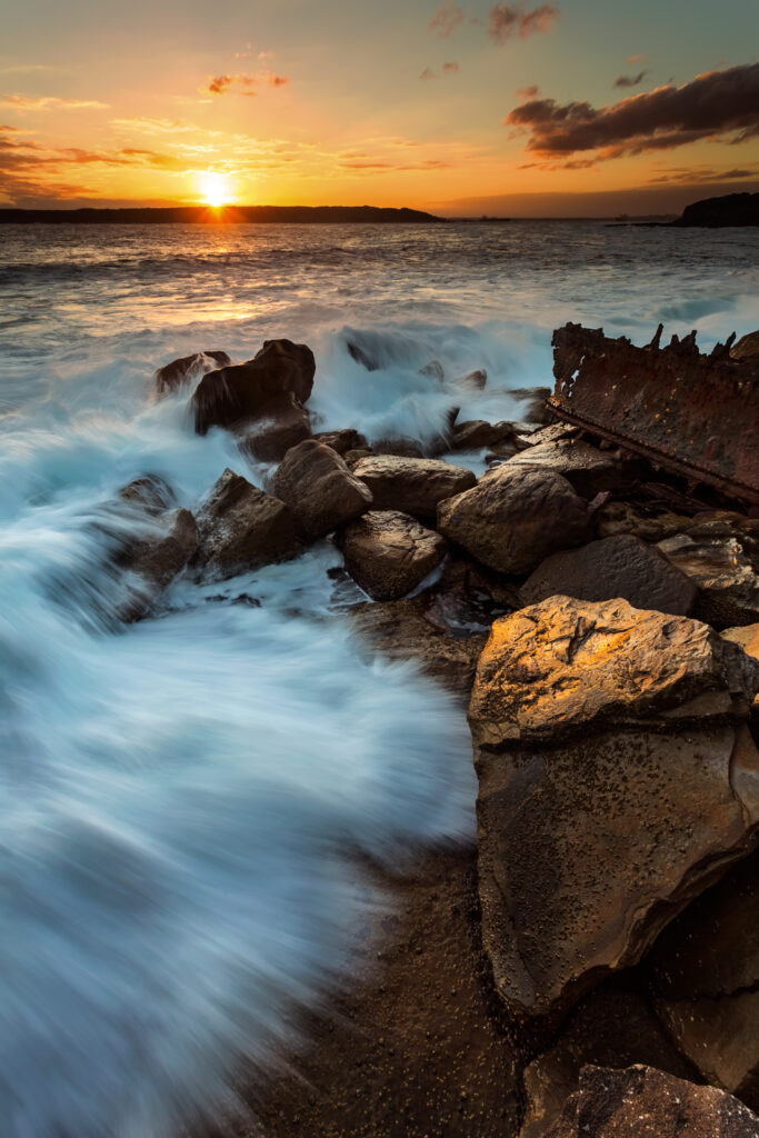Vibrant ocean wallpaper with crashing waves golden sunset rugged rocks dramatic coastal sky