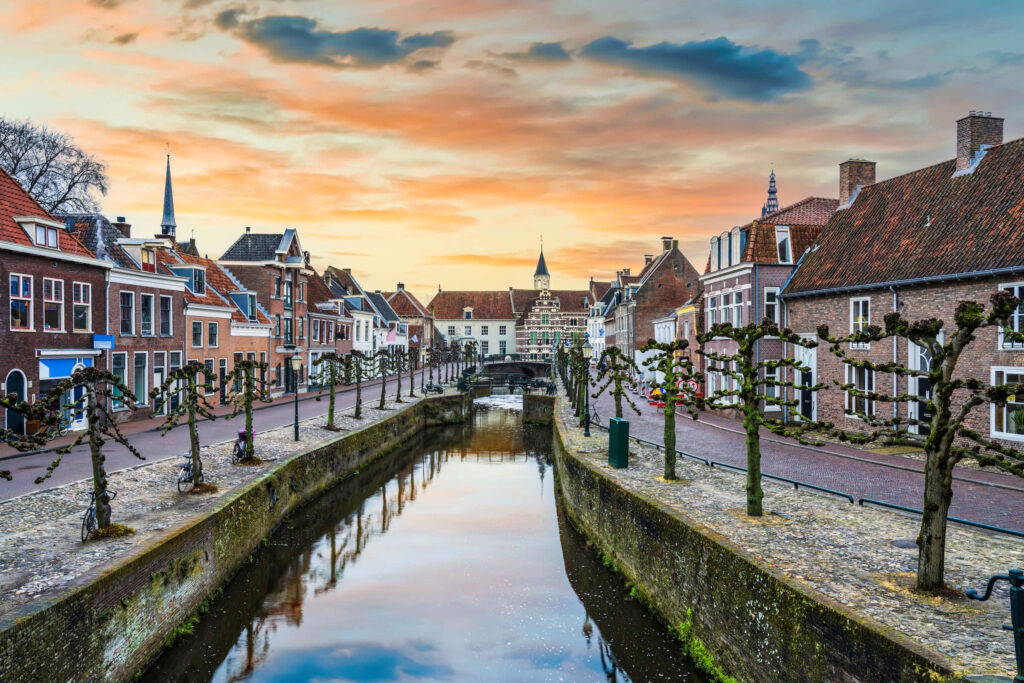 Historic Amersfoort canal at sunset with brick houses and trees reflecting in calm water wallpaper