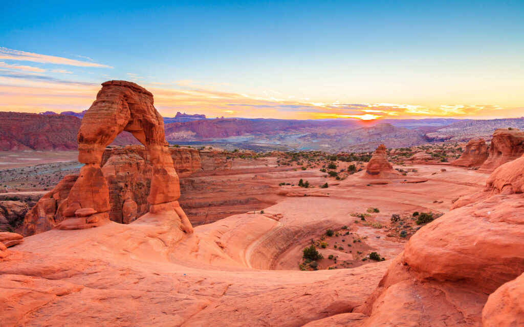 Sunset over Arches National Park red rock formations and iconic stone arch in desert landscape Wallpaper