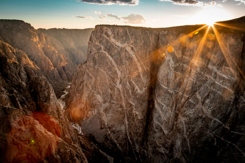 Sunset over Black Canyon Colorado cliffs glowing with golden light and dramatic rugged shadows Wallpaper