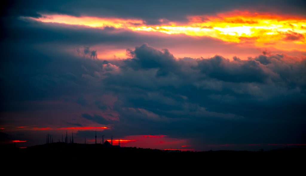 Sunset sky with vibrant orange red purple clouds and minaret silhouettes creating serene skyline Wallpaper
