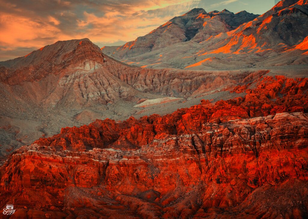 Sunset over rugged mountain peaks with warm orange red and gold tones scenic nature wallpaper