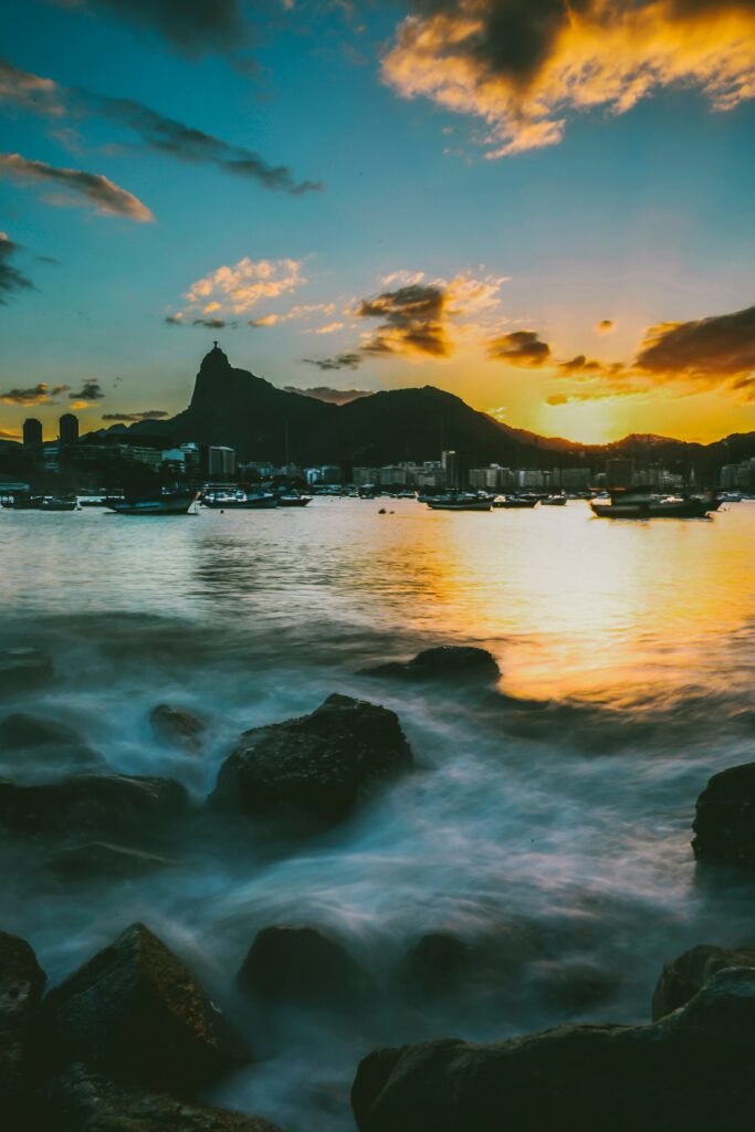 Sunset over tranquil port with golden light reflections boats calm water and mountain silhouette Wallpaper
