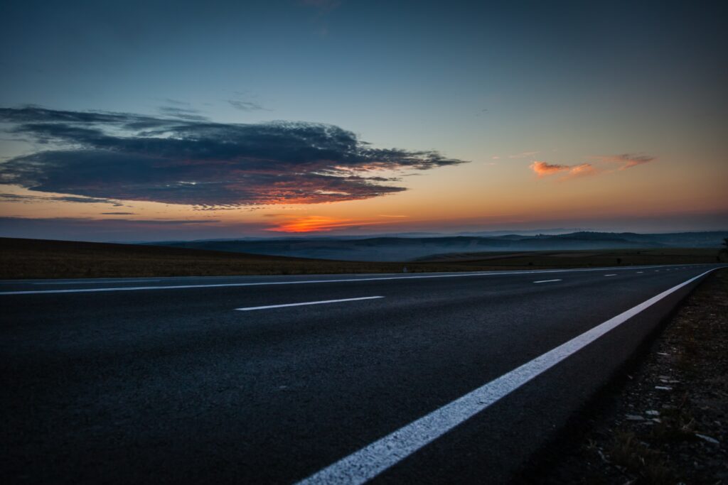 Quiet road under warm sunset sky with soft clouds peaceful solitude wallpaper background