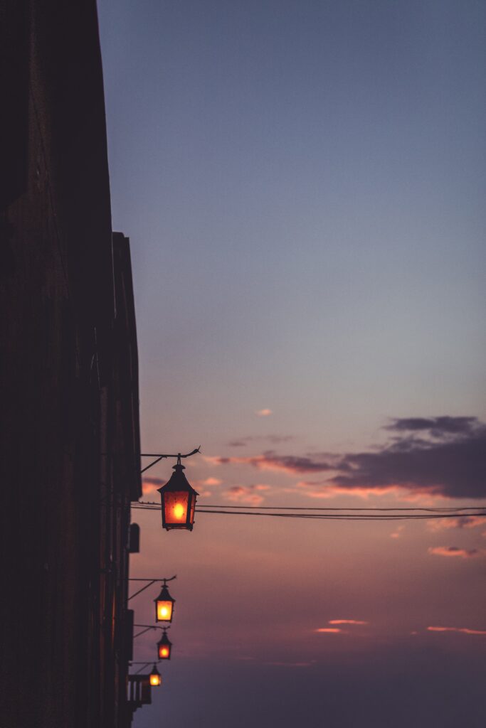 Soft lanterns glow on rooftop at sunset with purple orange sky urban evening ambiance wallpaper