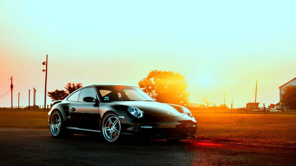 Sunset Glory: Captivating Snapshot of the Top 10 Car - Black Porsche 911 Amidst Scenic Background Wallpaper