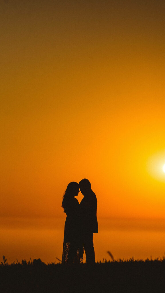 Romantic Silhouettes Embracing as Sun Dips Below the Horizon Wallpaper