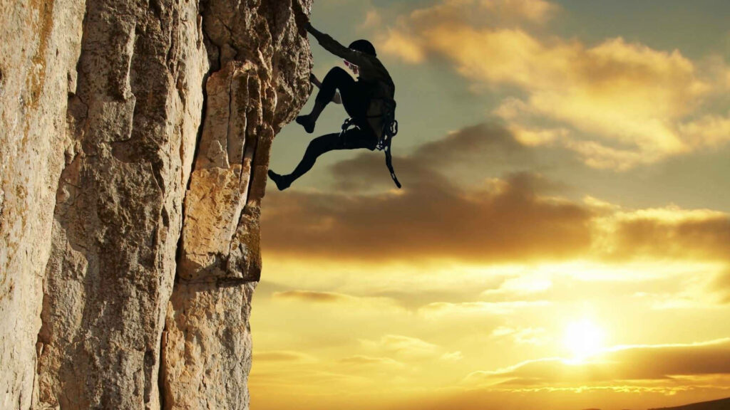 Climber scaling rugged rock face at golden sunset inspiring sport climbing adventure wallpaper