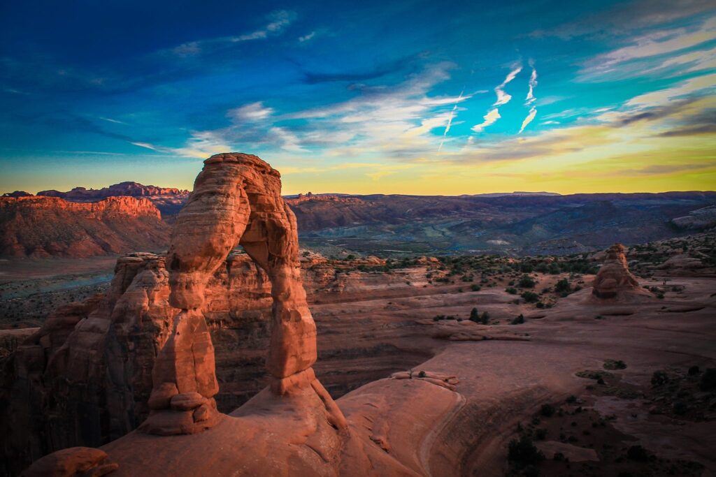 Stone arches at sunset with warm red and orange hues in a serene natural landscape wallpaper background
