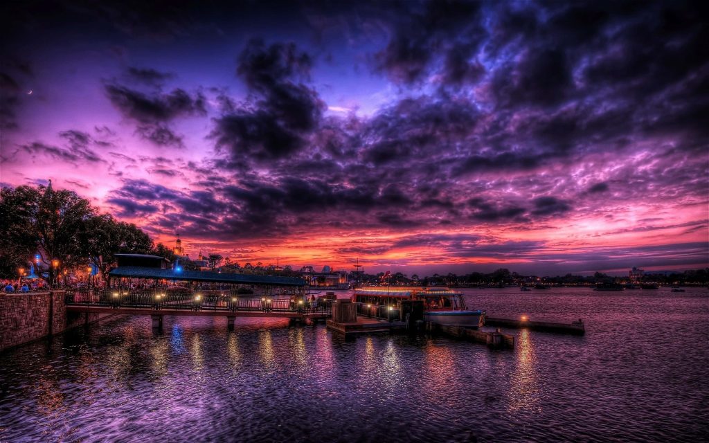 Friendship boat docked at Epcot World Showcase Lagoon during vibrant purple orange sunset reflection Wallpaper