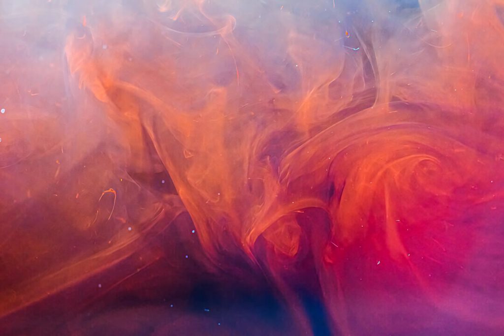 Surreal abstract wallpaper with vibrant orange red ink swirls flowing in water motion background