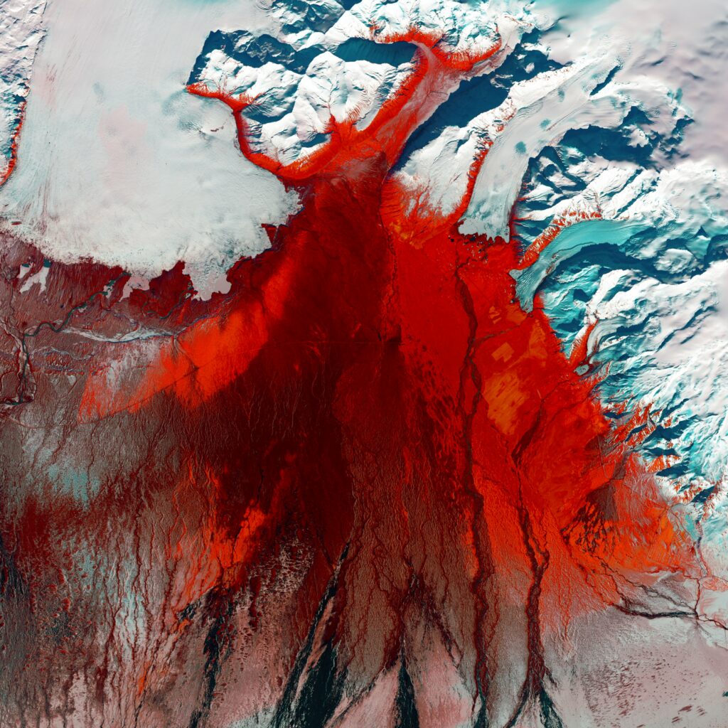 Aerial view of glacier with sharp ice formations and bold red hues creating surreal abstract art wallpaper