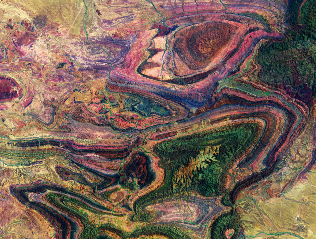 Aerial view of rugged mountains with vibrant purple green and brown patterns and textured relief Wallpaper