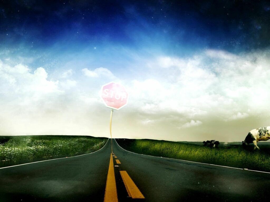 Surreal open road with yellow markings through field under blue sky and whimsical stop sign Wallpaper