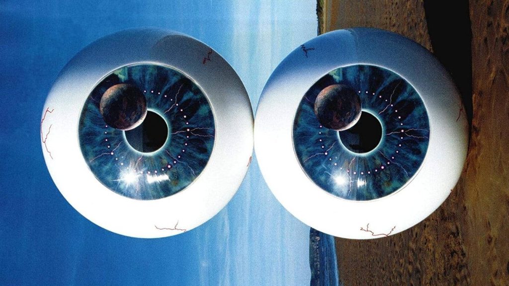 Surreal Pink Floyd Pulse wallpaper with giant cosmic eyes and galaxy irises over sandy beach