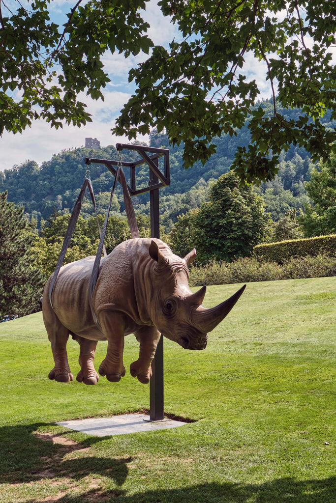 Surreal Rhinoceros Wallpaper: Nature Meets Fantasy in Lush Landscape