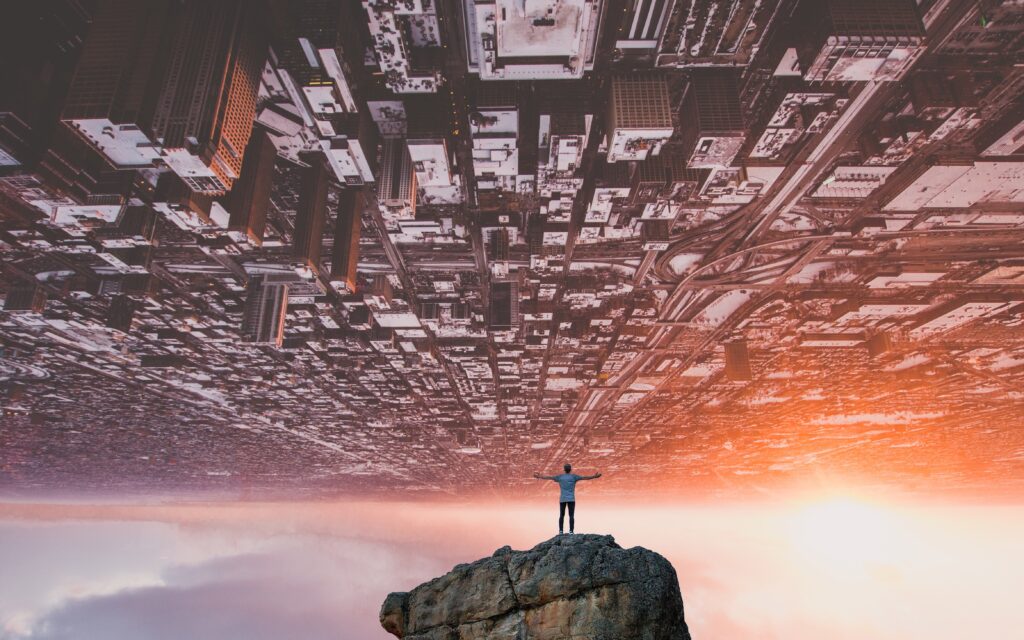 Surreal Wallpaper: Man on Rock gazes at Inverted Cityscape Sunset